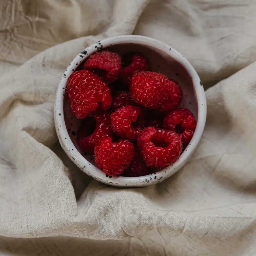 Himbeeren sind in einer kleinen Schale. Die Schale liegt auf einem Leinentuch.