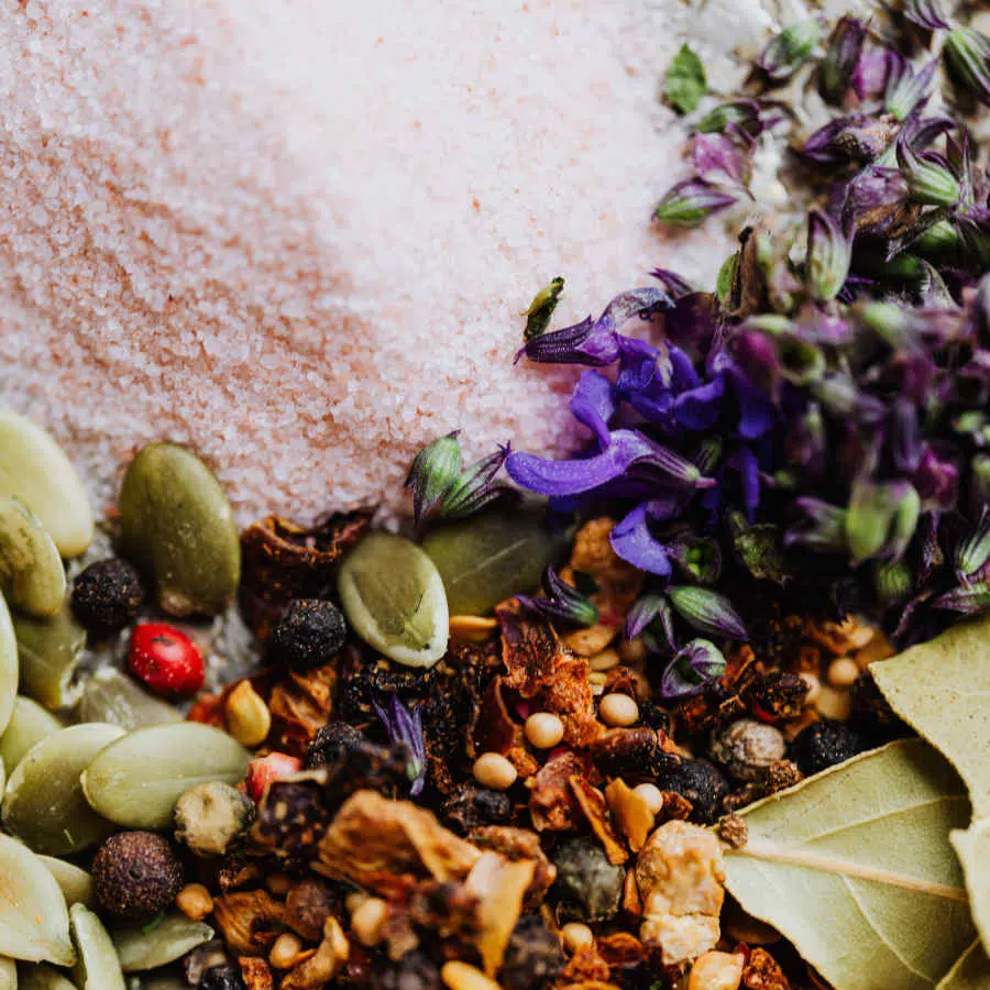 Verschiedene Gewürze und Kräuter liegen beieinander. Zu sehen ist außerdem rosafarbenes Salz.