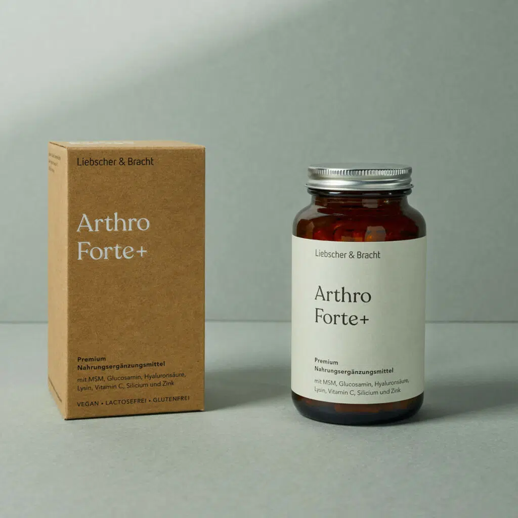 Eine Braunglasflasche und ein Faltkarton jeweils mit der Beschriftung Arthro Forte Plus stehen vor einem grünen Hintergrund.