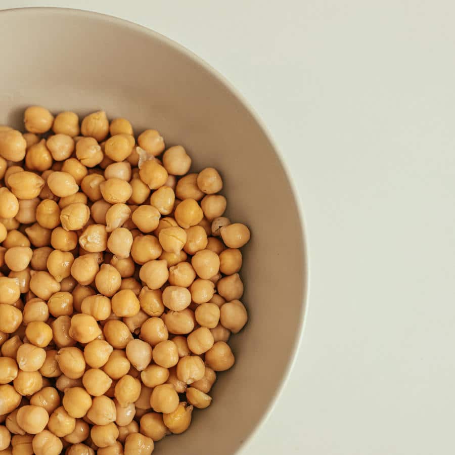 Eine beigefarbene Schale ist voll mit Kichererbsen.