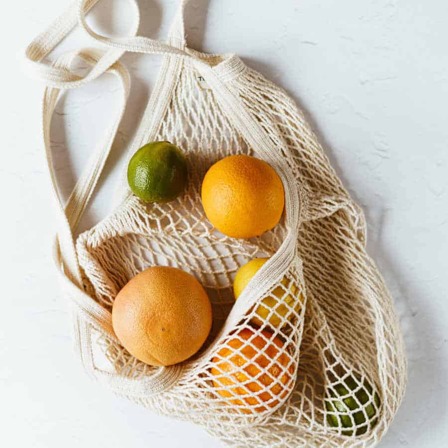 Verschiedene Zitrusfrüchte liegen in einem weißen Einkaufsnetz