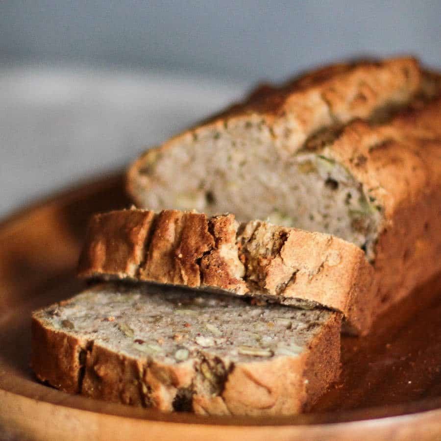 Ein Brotlaib auf einem braunen Brettchen ist zu sehen. Vom Brot sind bereits zwei Scheiben abgeschnitten, die vor dem Rest des Laibes liegen.
