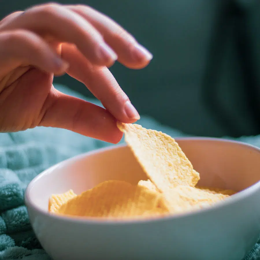 Eine Hand greift nach einem Chip in einer Schüssel voller Chips.