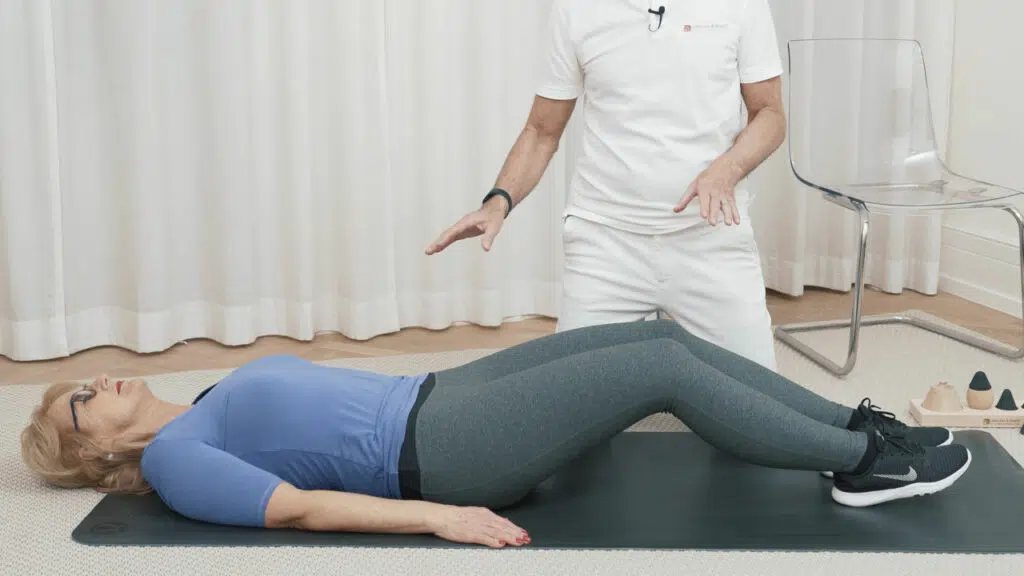 Eine Frau liegt mit dem Rücken auf dem Boden und hat die Beine leicht angewinkelt.