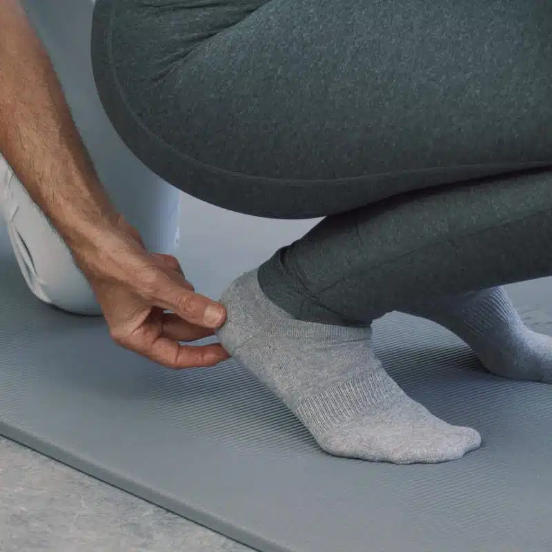 Eine Person ist in die Hocke gegangen und hat dabei ihre Fersen leicht angehoben.