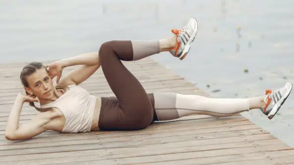 Eine Frau auf einem Bootssteg übt ein Bauchtraining zur Kräftigung aus.