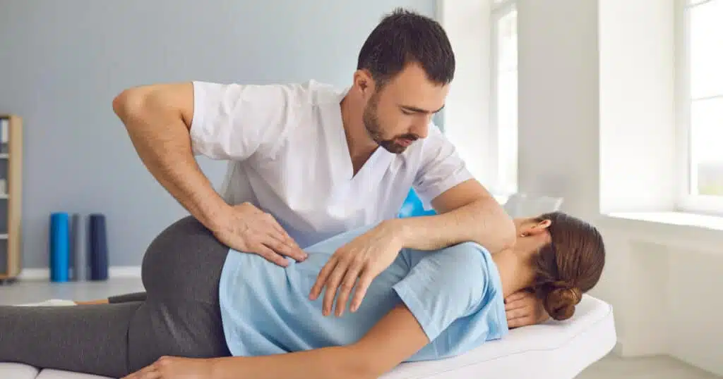 Ein Therapeut führt eine manuelle Therapie an einer Patientin durch