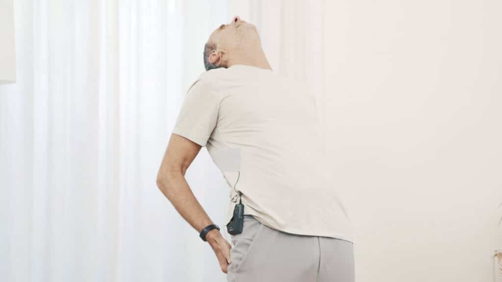 Roland Liebscher-Bracht hat beide Hände auf dem Gesäß abgestützt und lehnt sich nach hinten in eine Rückbeuge. Dabei hat er auch den Kopf nach hinten gelehnt.