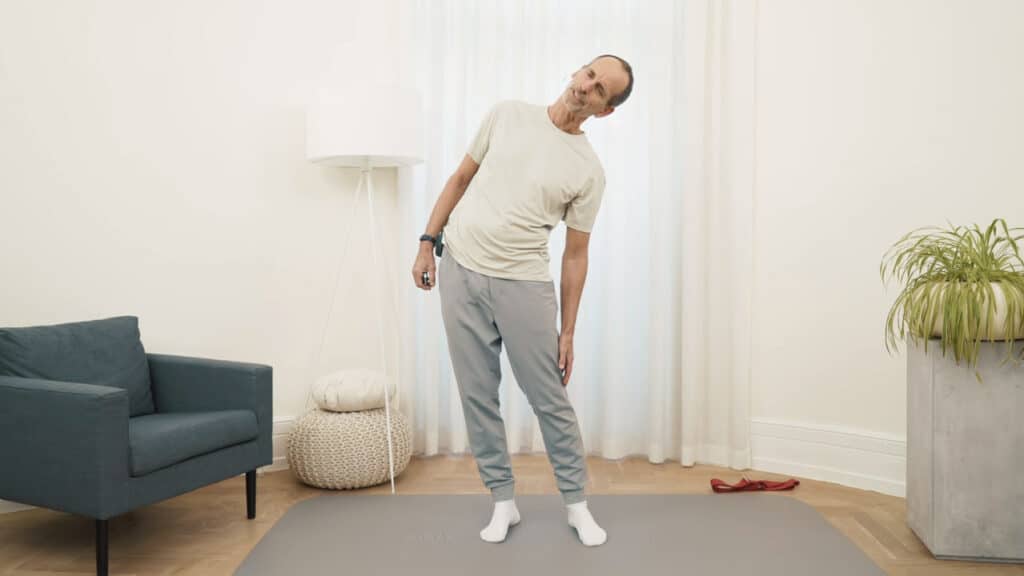 Roland Liebscher-Bracht steht auf einer Matte und lehnt sich nach links in eine Seitbeuge.