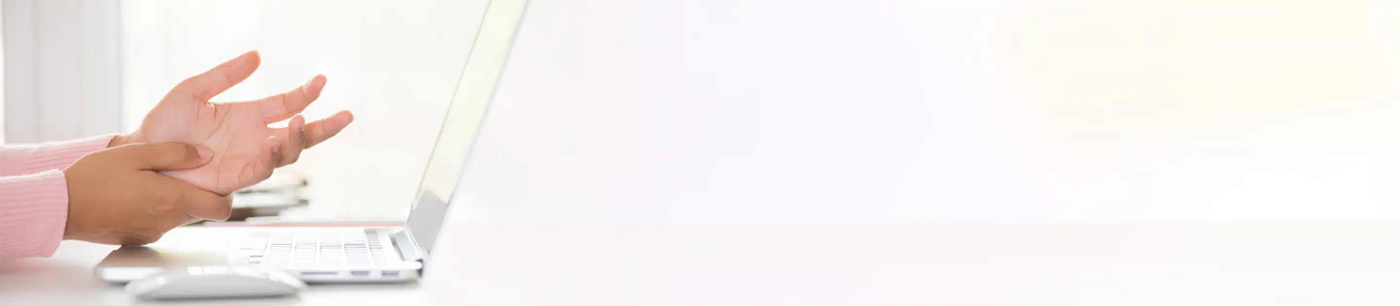 eine Hand reibt die Handfläche der anderen über einem Laptop