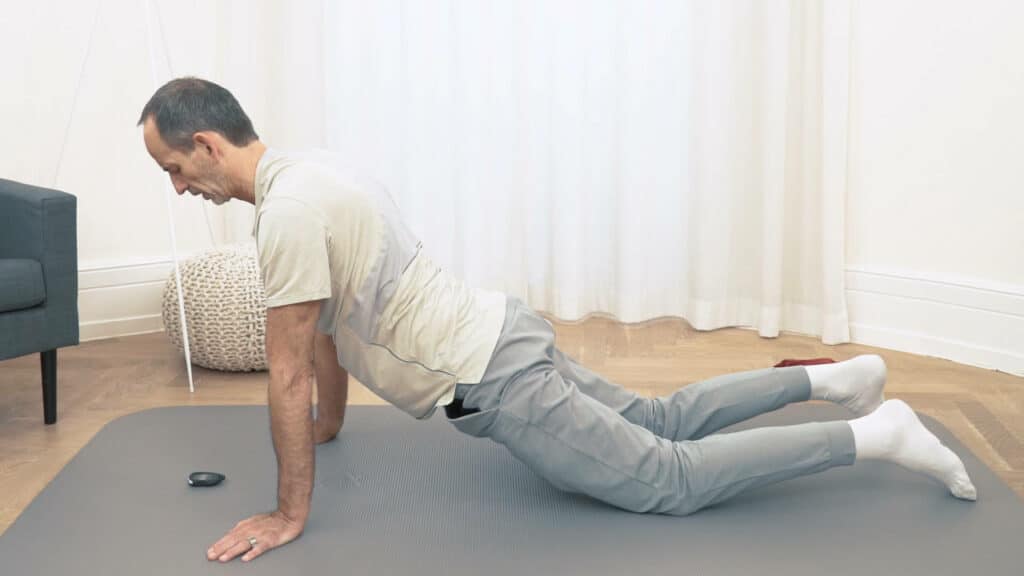 Roland Liebscher-Bracht kniet und stützt sich mit beiden Armen am Boden ab, während er seine Leiste nach vorne schiebt.