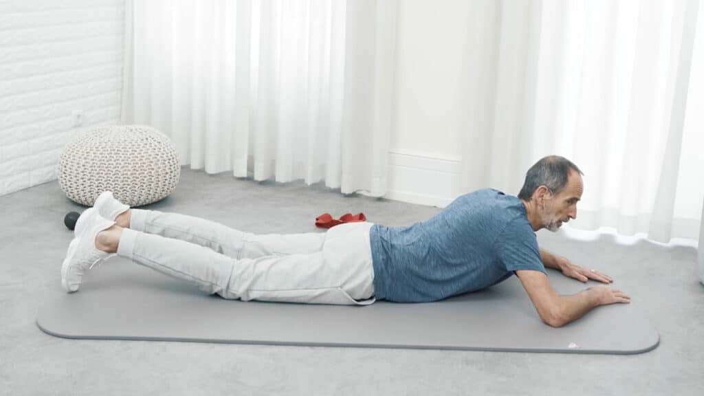 Roland Liebscher-Bracht befindet sich in Bauchlage auf der Übungsmatte.