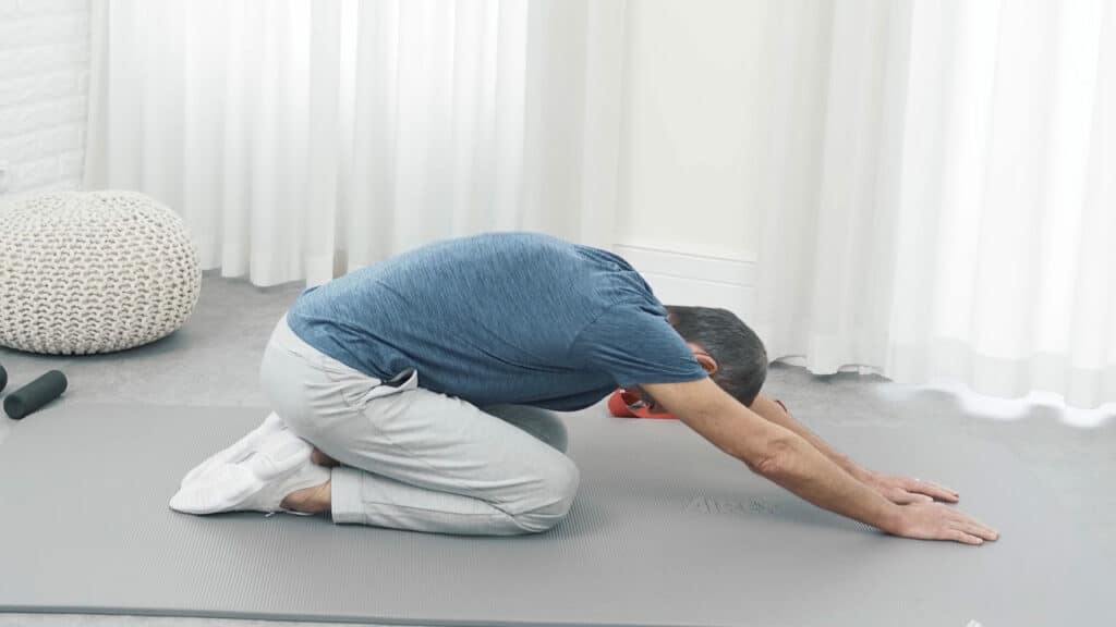 Roland Liebscher-Bracht sitzt auf der Ferse und hat seinen Oberkörper weit nach vorne gebeugt.