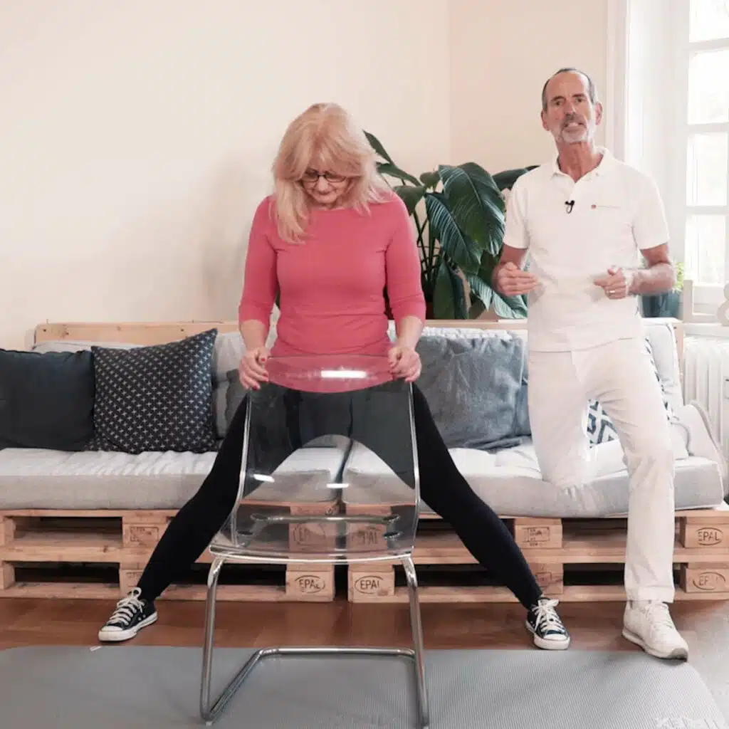 Die Patientin hält sich mit den Händen an einer Stuhllehne fest und hat die Beine weit geöffnet.