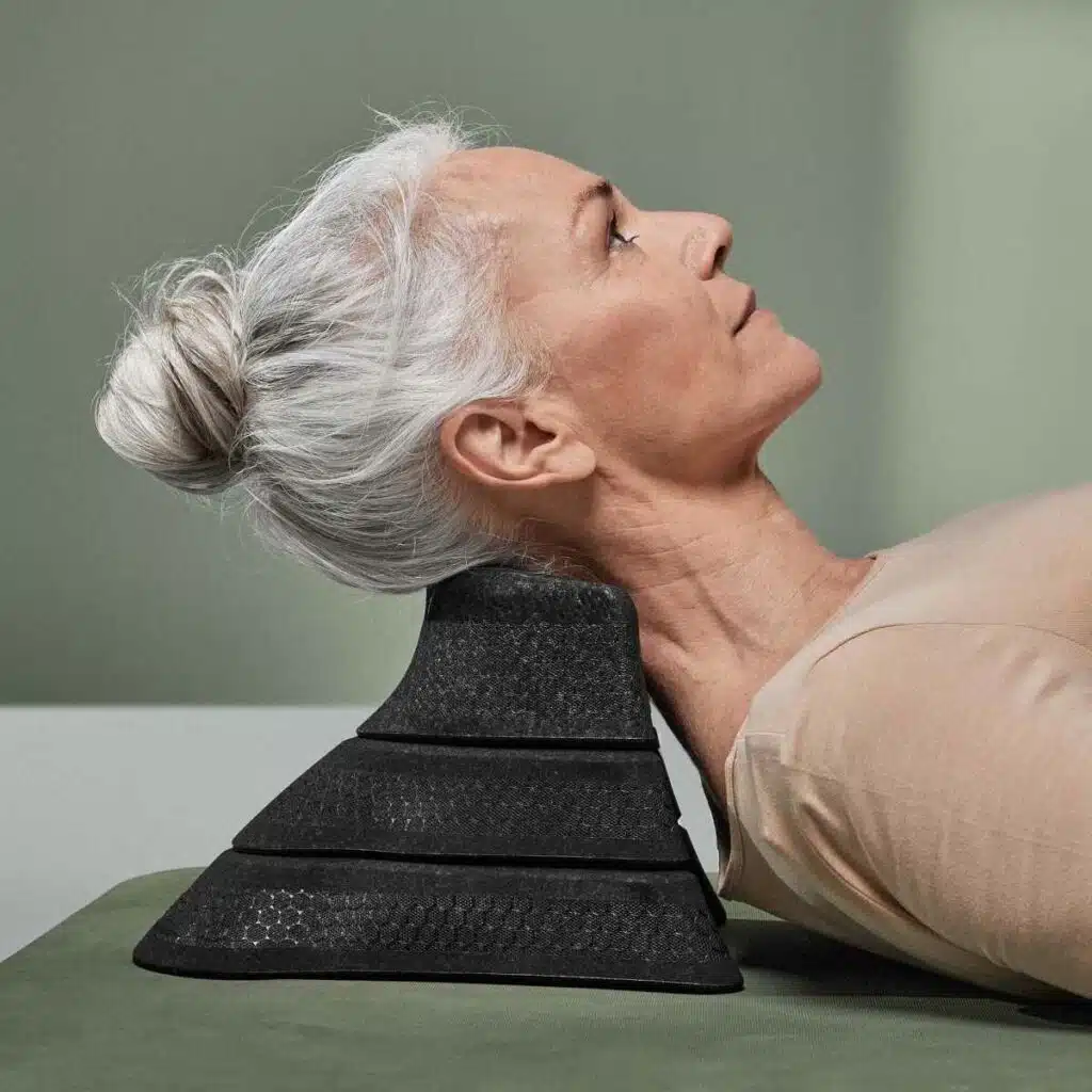 Der Betrachter blickt von der Seite auf eine Frau, die ihren Kopf auf dem Liebscher & Bracht Nackenretter platziert hat.