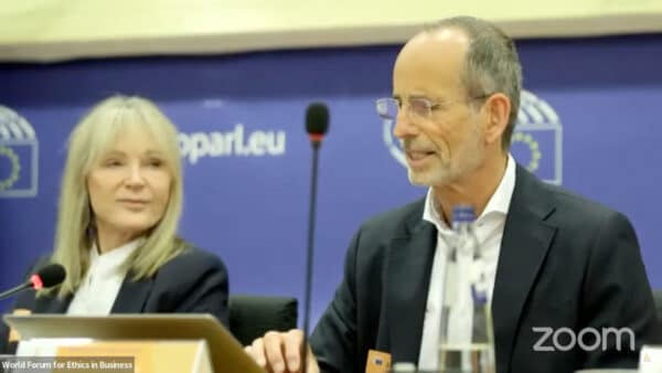 Roland Liebscher-Bracht und Petra Bracht sind auf dem World Forum For Ethics in Business zu sehen. Roland Liebscher-Bracht spricht in ein Mikrofon.
