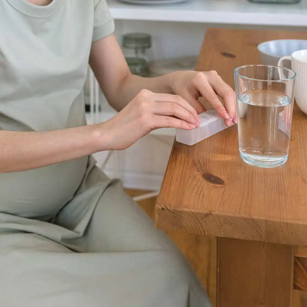 Eine Schwangere entnimmt einer Pillendose Tabletten.