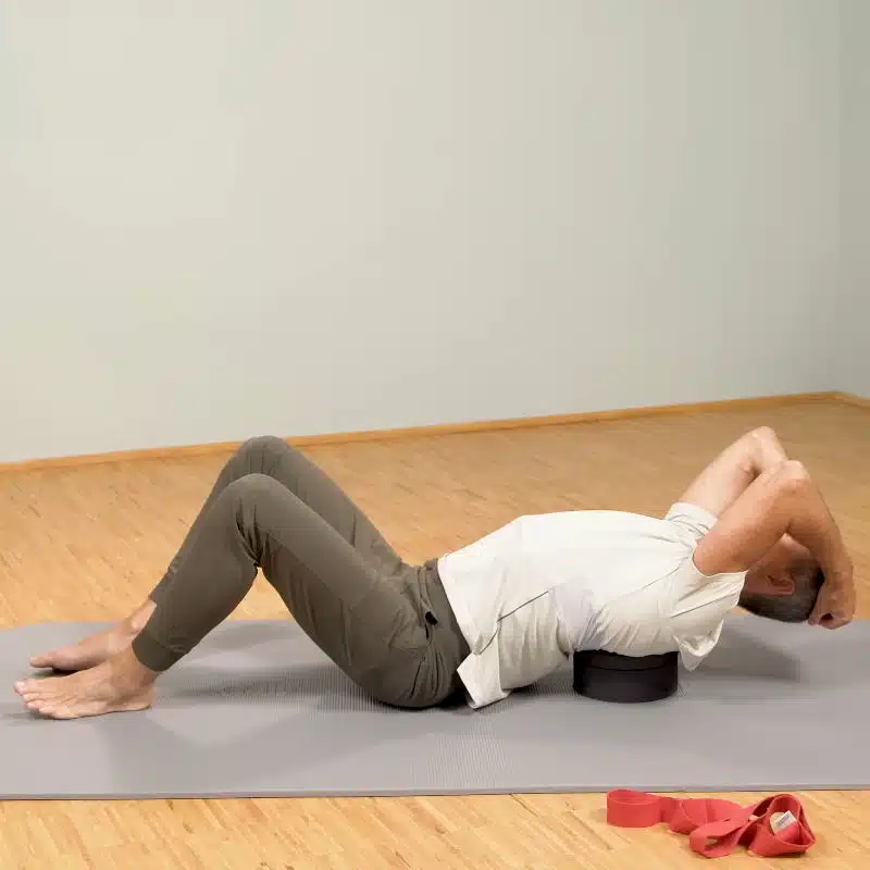 Roland Liebscher-Bracht liegt am Boden auf dem Rückenretter und zeigt eine Übung.