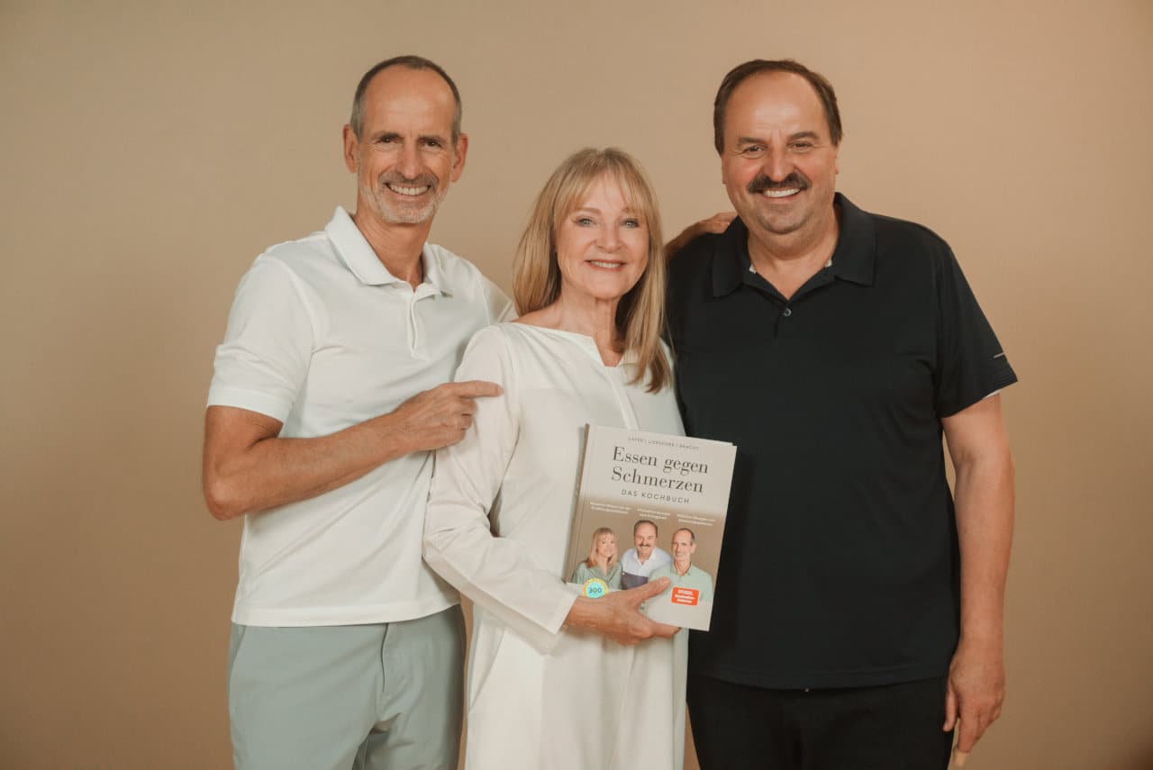 Roland Liebscher-Bracht, Petra Bracht und Johann Lafer posieren gemeinsam mit ihrem neuen Buch "Essen gegen Schmerzen"