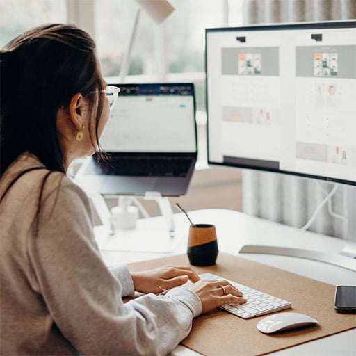 Eine junge Frau arbeitet an einem Schreibtisch und schaut dabei in einen Monitor.