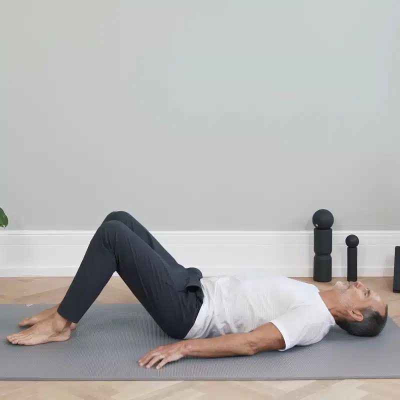 Roland Liebscher-Bracht liegt in Rückenlage am Boden. Seine Beine sind aufgestellt und angewinkelt.