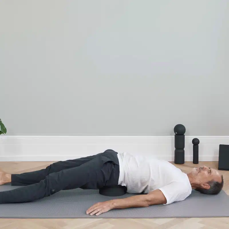 Roland Liebscher-Bracht liegt mit ausgestreckten Armen und Beinen auf einem Rückenretter.