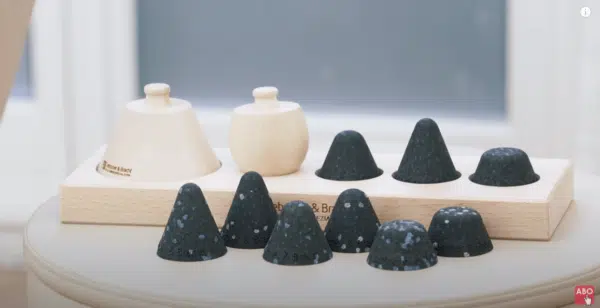 Das Liebscher & Bracht Schmerzfrei-Drücker-Set ist zu sehen: Ein kugel- und ein kegelförmiger Holzgriff sowie schwarze Aufsätze in unterschiedlichen Härtegraden.
