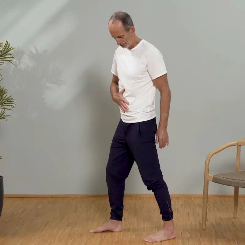 Roland Liebscher-Bracht steht in leichter Schrittstellung und hat eine Hand auf seinen Bauch gelegt.