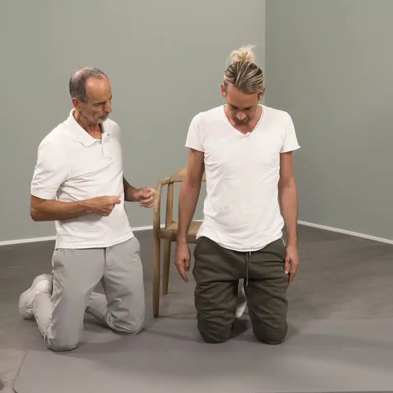 Roland Liebscher-Bracht und ein weiterer Mann knien nebeneinander und schauen auf den Boden.