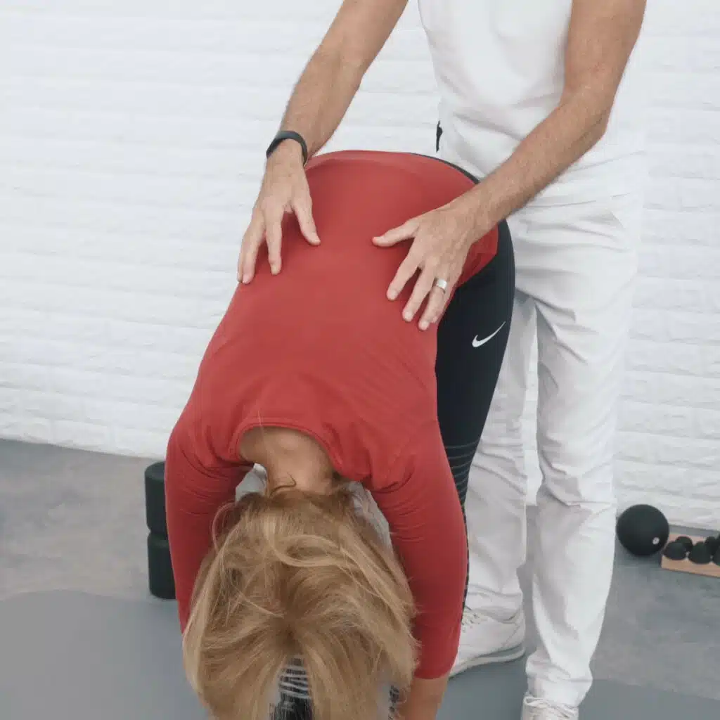 Eine Person steht in der stehenden Vorbeuge, mit gestreckten Beinen und hängendem Oberkörper. Auch der Kopf hängt nach unten.