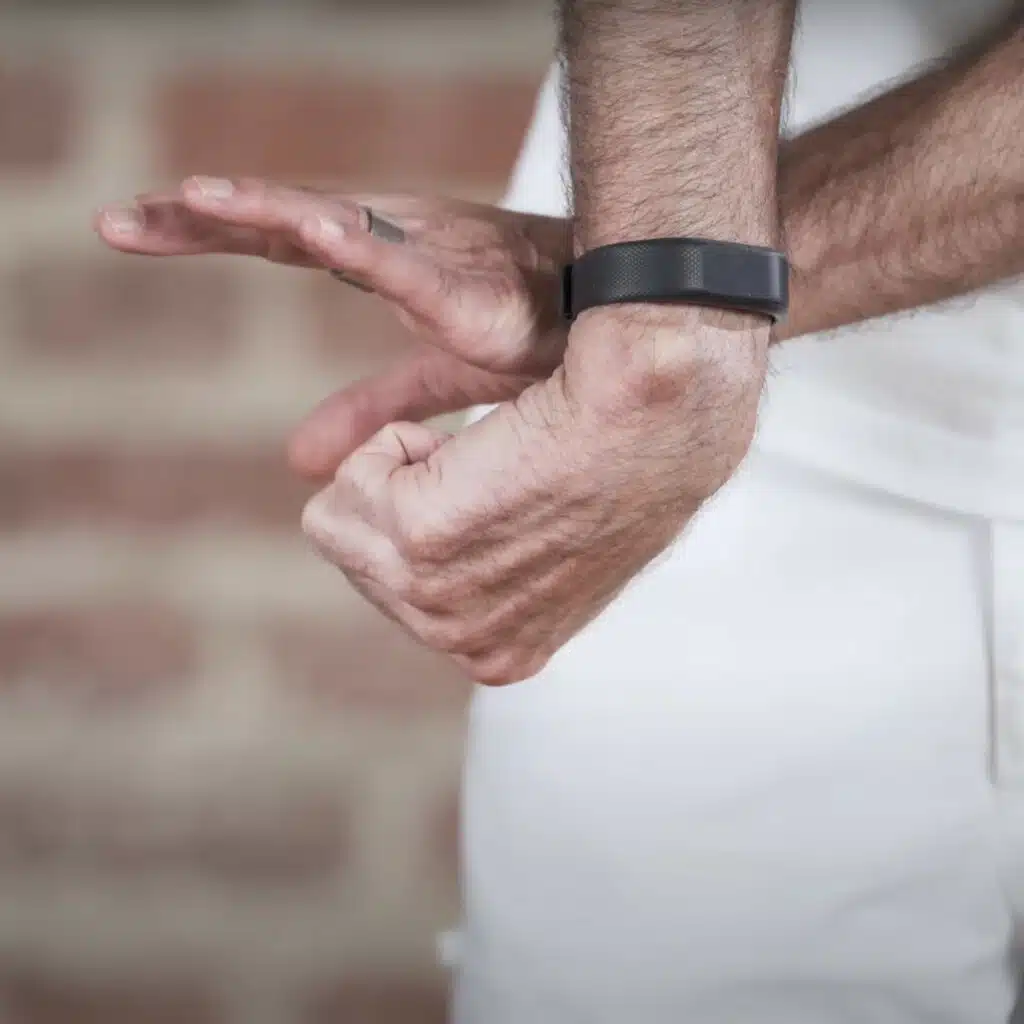 Nahaufnahme der Hände einer Person. Der rechte Arm ist nach innen rotiert und die Faust zum Unterarm eingeklappt. Die linke Hand greift sich die rechte Faust.