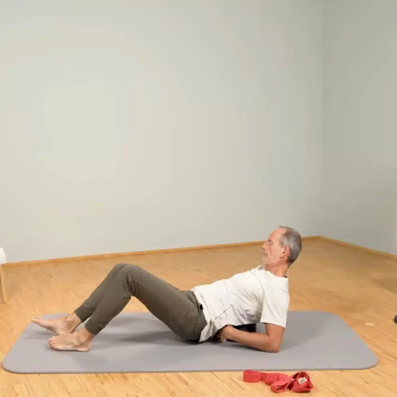 Roland Liebscher-Bracht liegt am Boden auf dem Rückenretter und bereitet eine Übung vor.