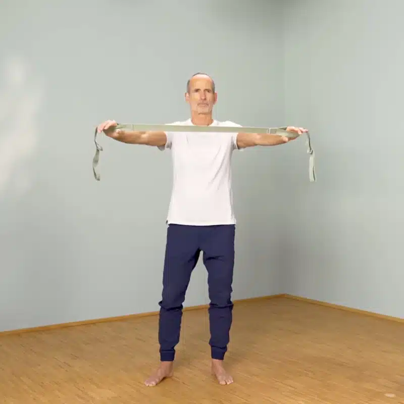 Roland Liebscher-Bracht steht mit nach vorne gestreckten Armen aufrechtda und hält den Schulterretter in den Händen.