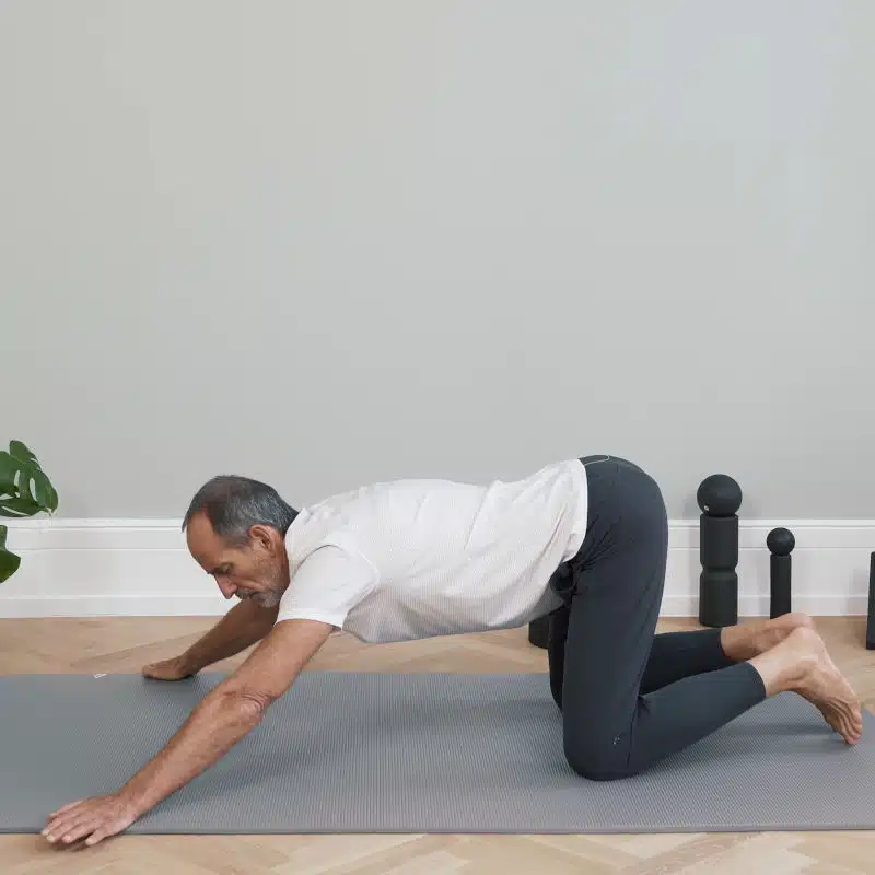 Roland Liebscher-Bracht ist am Boden auf allen vieren und hat die Arme nach vorne zur Seite ausgestreckt.