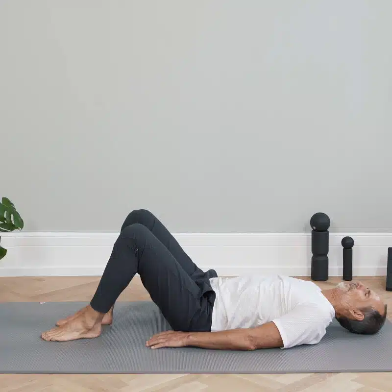 Roland Liebscher-Bracht liegt mit dem Rücken am Boden und hat seine Beine aufgestellt.