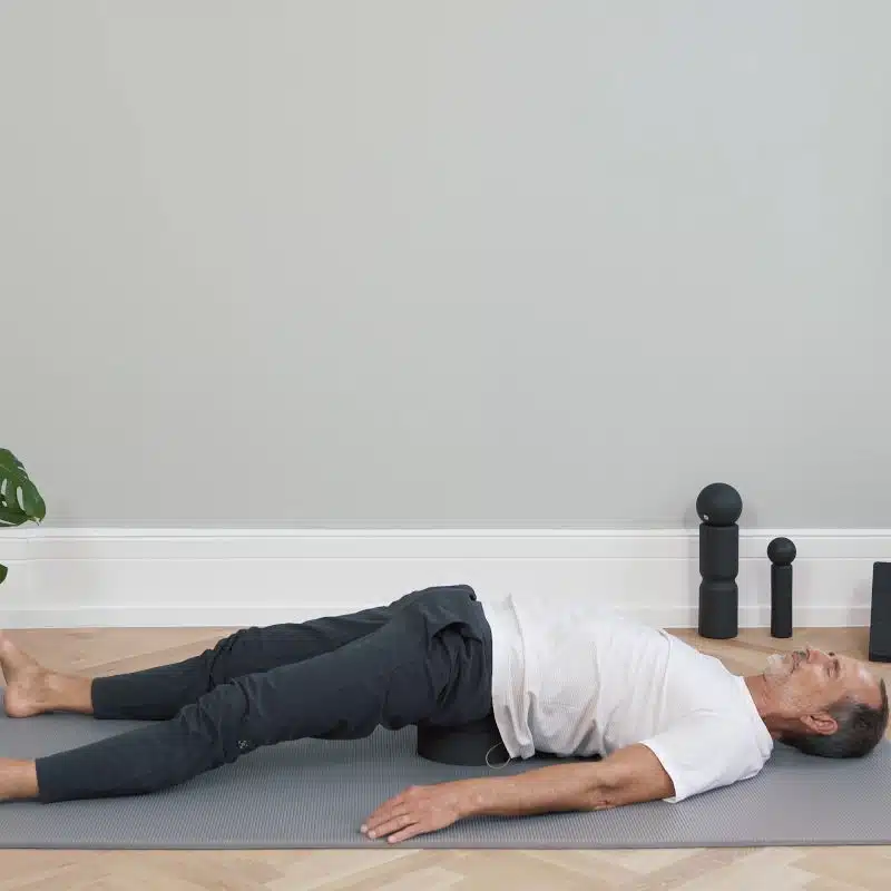 Roland Liebscher-Bracht liegt mit dem Gesäß auf einem Rückenretter und hat die Beine ausgestreckt.