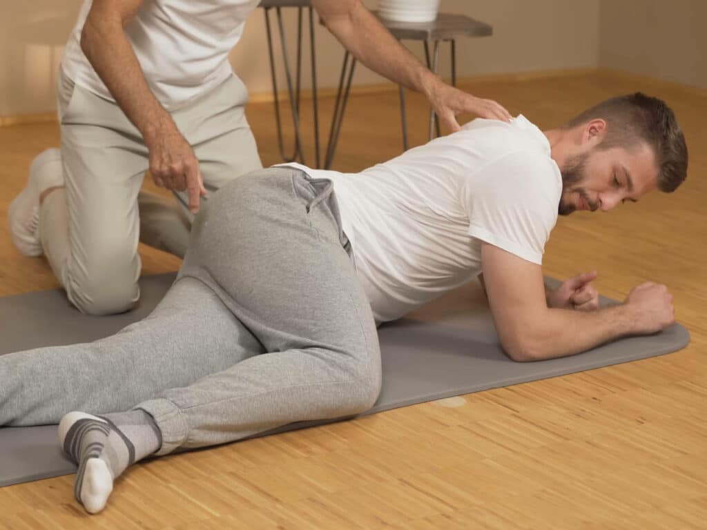 Ein Mann liegt seitlich am Boden und stützt seinen Oberkörper auf beiden Unterarmen ab.