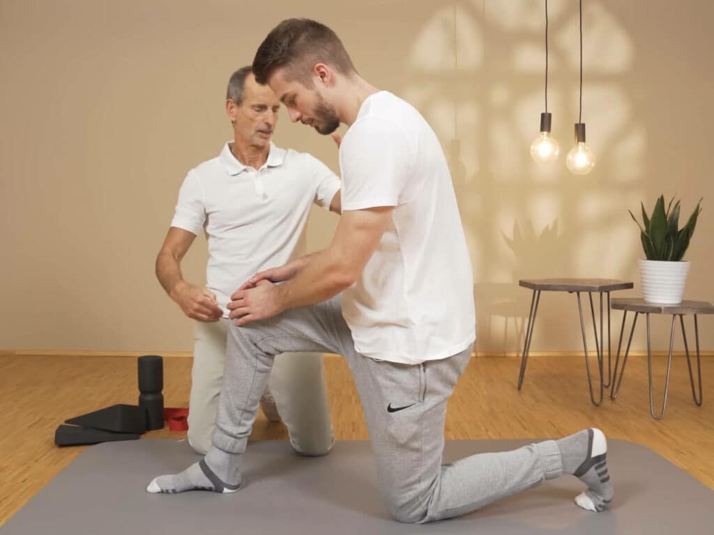 Ein Mann kniet mit einem Bein am Boden und hat das andere Bein aufgestellt.