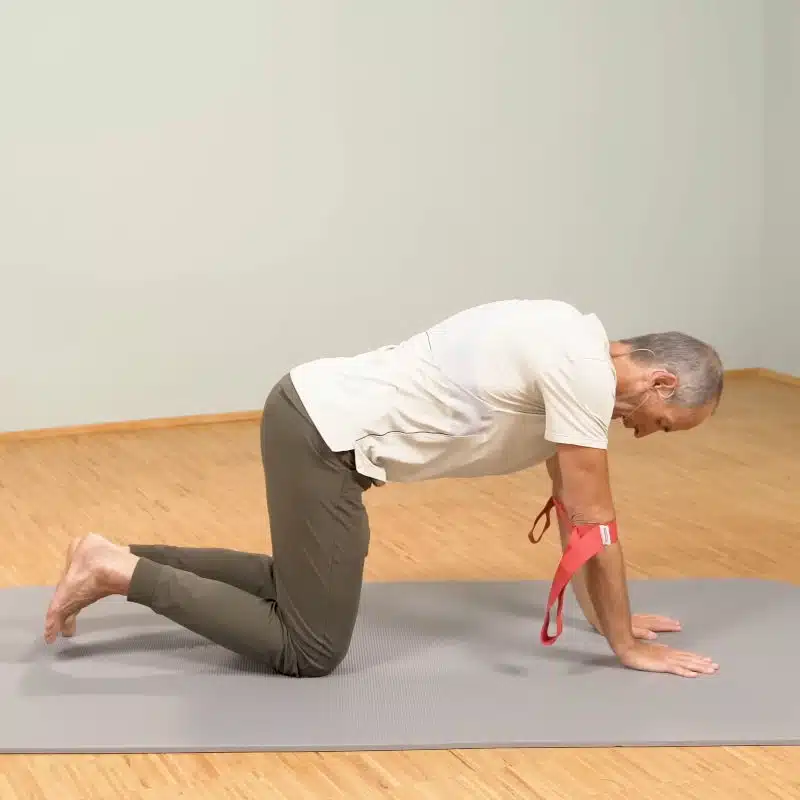 Roland Liebscher-Bracht ist auf allen vieren. Um seine Ellenbogen hat er eine rote Schlaufe gewickelt.