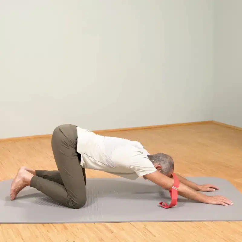 Roland Liebscher-Bracht zeigt eine Dehnübung. Dazu kniet er und stützt seinen Oberkörper mit ausgestreckten Armen am Boden ab.