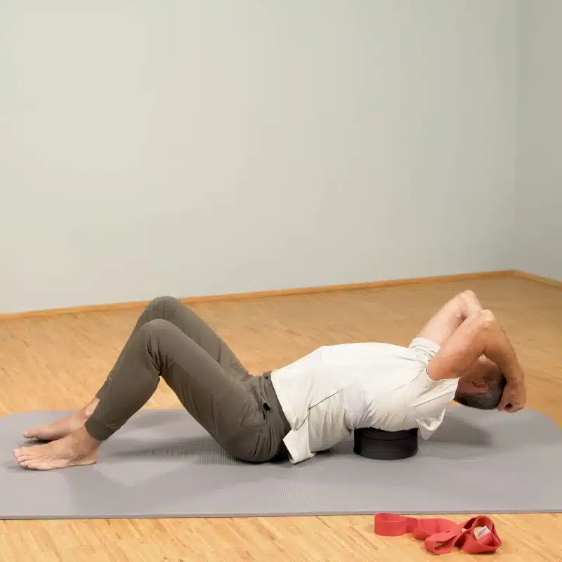 Roland Liebscher-Bracht liegt mit seinem Oberkörper auf dem Rückenretter und hält seinen Kopf mit beiden Armen fest.