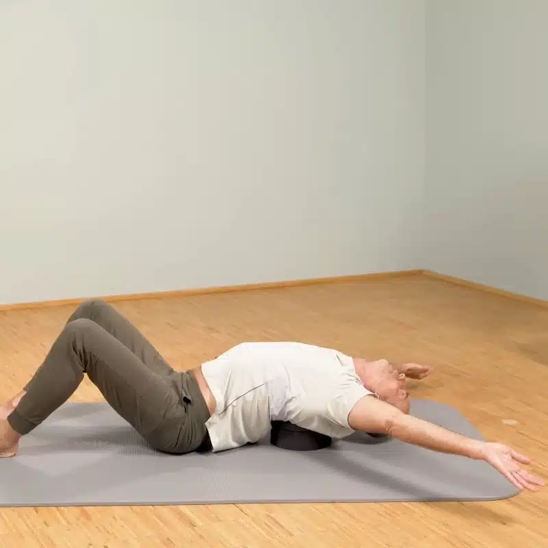 Roland Liebscher-Bracht liegt mit seinem Oberkörper auf dem Rückenretter und hat die Arme seitlich ausgestreckt.