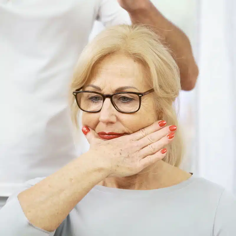 Eine Frau hält die rechte Hand an ihren Unterkiefer.