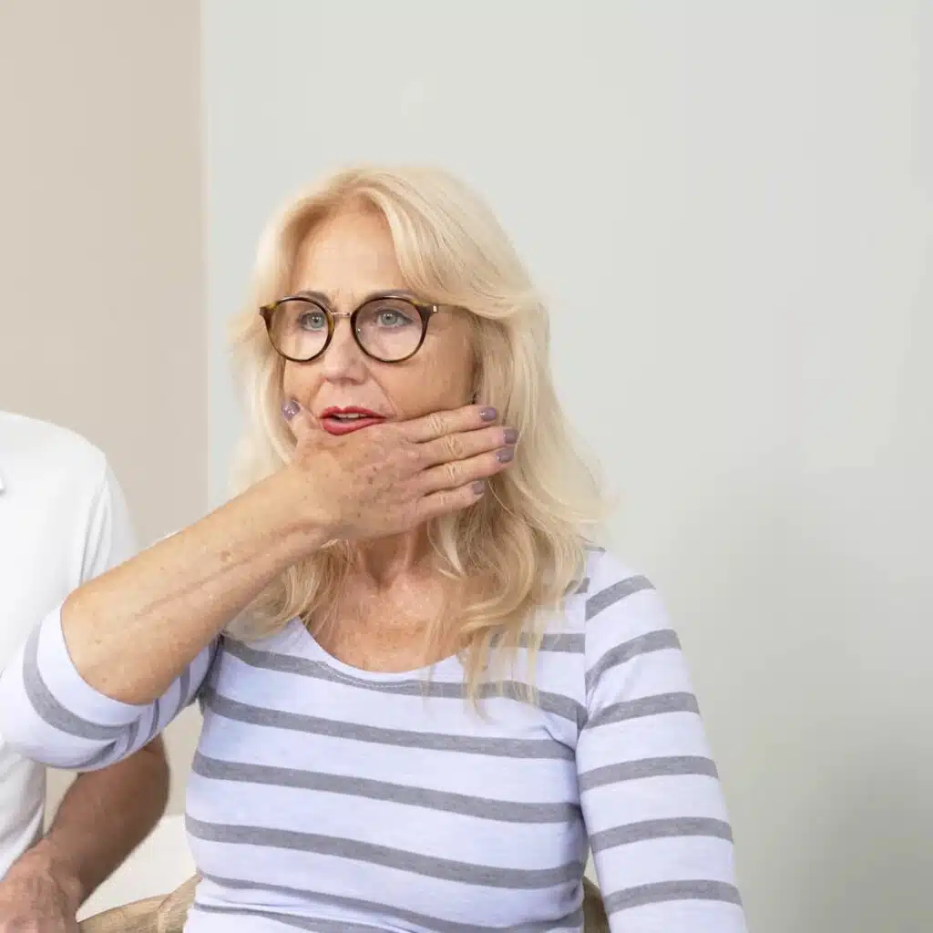 Eine Person hat die rechte Hand an den Unterkiefer gelegt. Der Daumen ist abgespreizt, sodass das Kinn genau zwischen Daumen und Zeigefinger liegt.