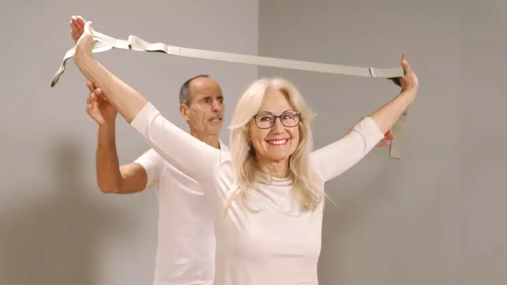 Eine Person hat die Hände in die Schlaufen des Schulterretters gesteckt. Die Arme sind gestreckt und sie hält sie weit geöffnet über den Kopf.