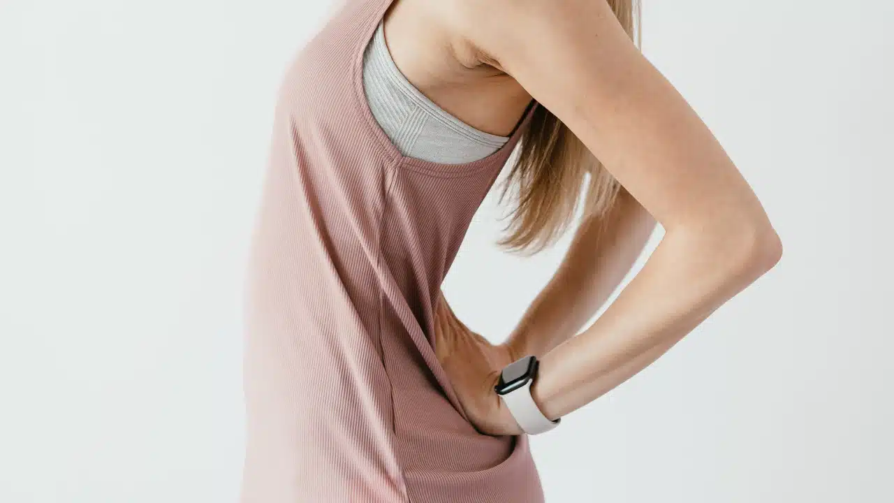 Eine Person hat beide Hände auf den unteren Rücken abgelegt. Sie schiebt ihren Bauch nach vorne raus und lehnt sich mit dem Oberkörper zurück.