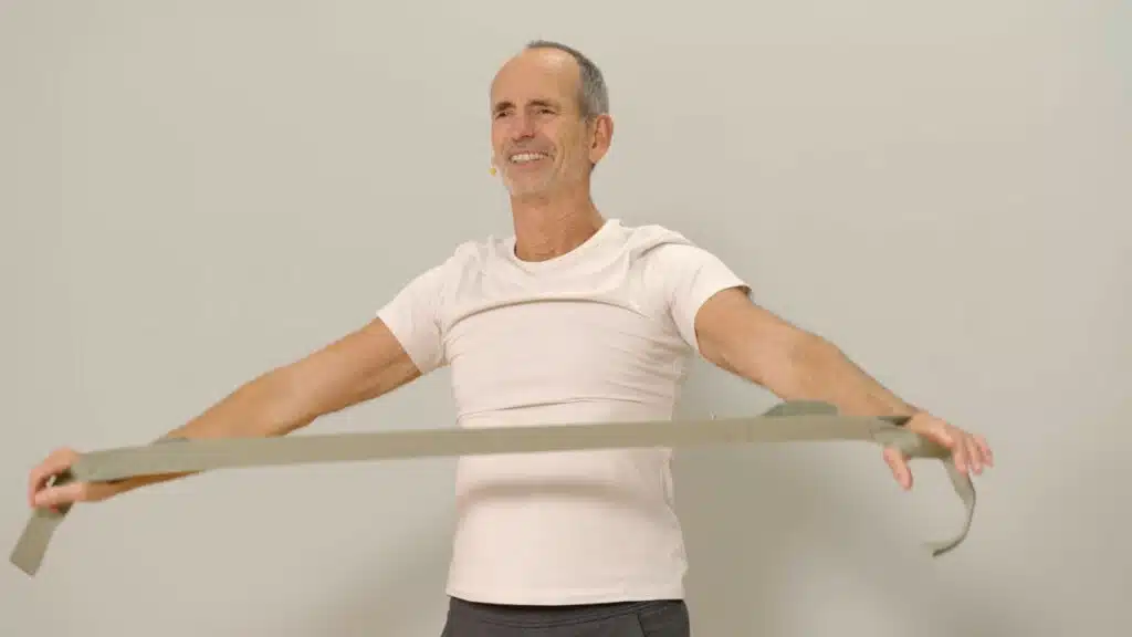 Eine Person hat beide Hände in den Schlaufen des Schulterretters eingefädelt. Sie streckt die Arme vor den Körper, die Arme sind gestreckt und der Schulterretter ist auf Spannung gebracht.