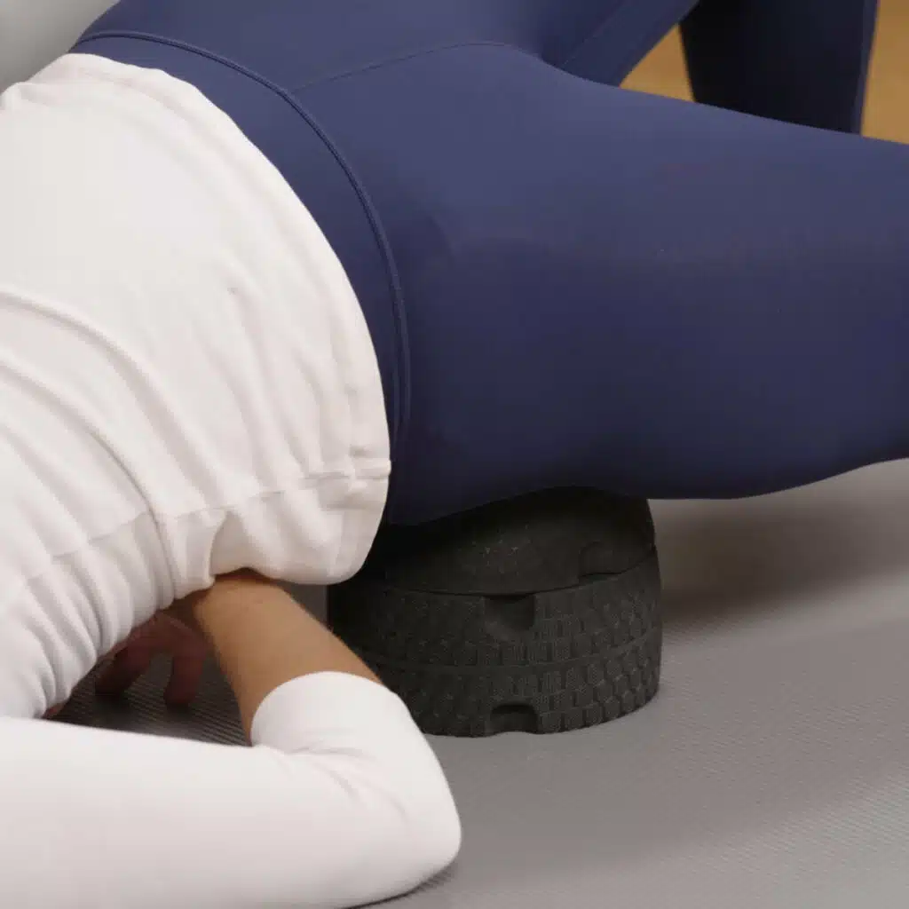 Eine Person liegt mit der rechten Gesäßhalte auf dem ISG-Ischias-Retter. Das rechte Bein ist gestreckt, das linke aufgestellt.