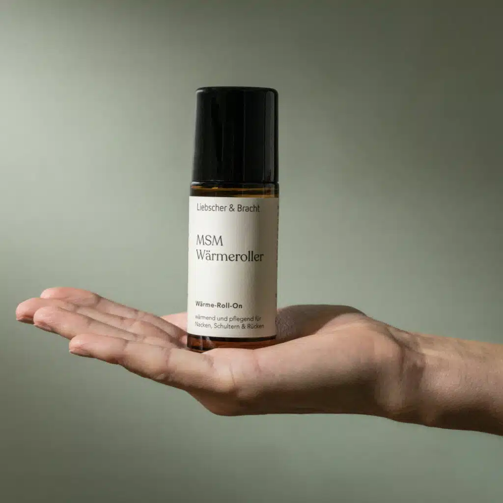 Auf einer Handfläche steht ein kleines Glasfläschchen. Dabei handelt es sich um den MSM Wärmeroller von Liebscher & Bracht.