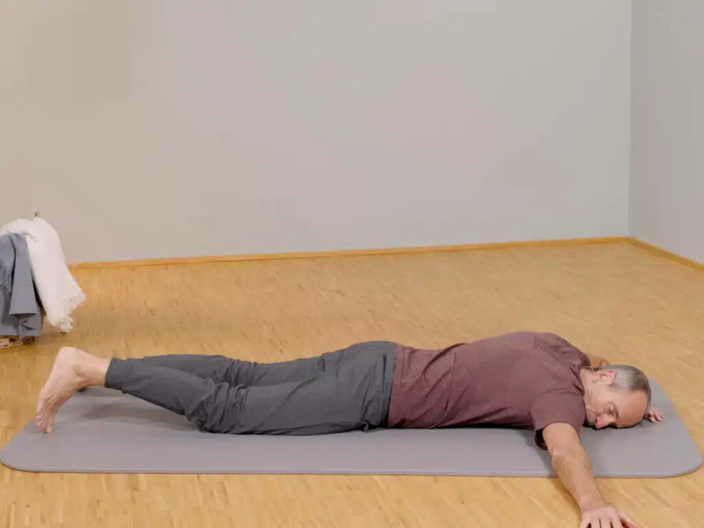 Roland Liebscher-Bracht liegt bäuchlings auf dem Boden und hat einen Arm gerade zur Seite ausgestreckt.